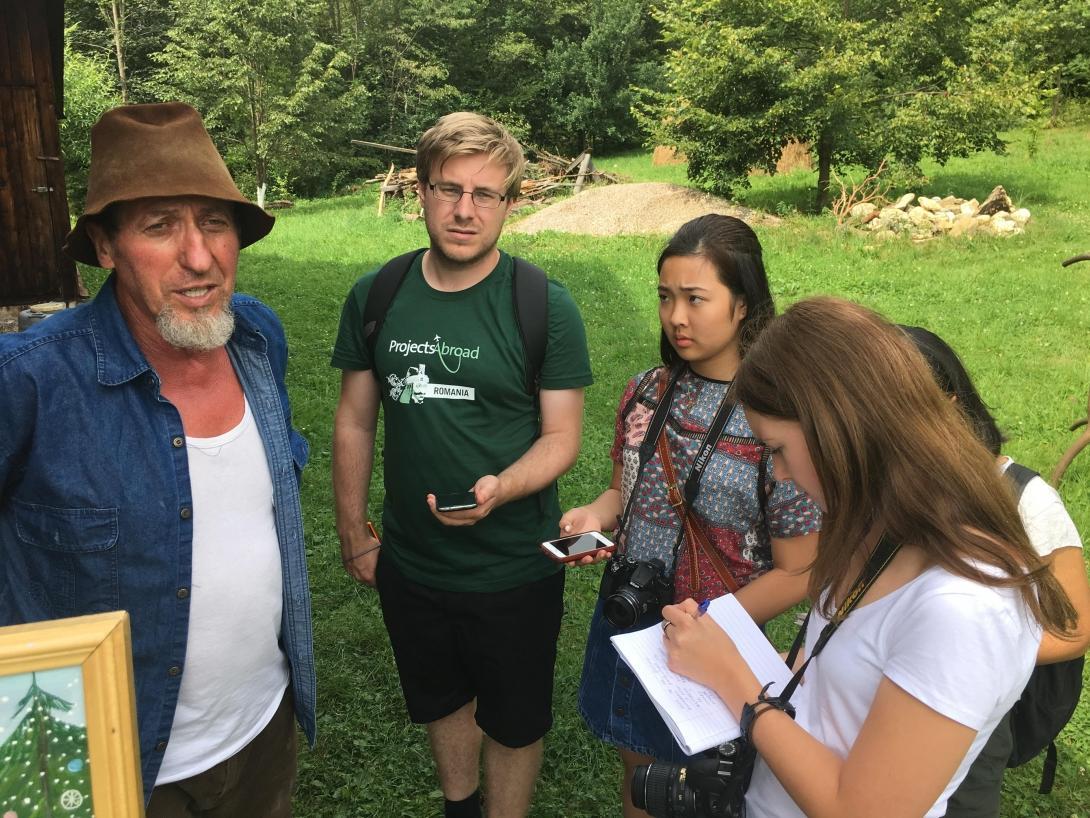 A Romanian wood carver is interviewed for a magazine by several students doing Journalism internships abroad.